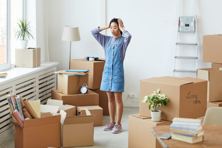 Frustrated Asian woman panicking while standing among cardboard boxes, cost-saving tips for moving